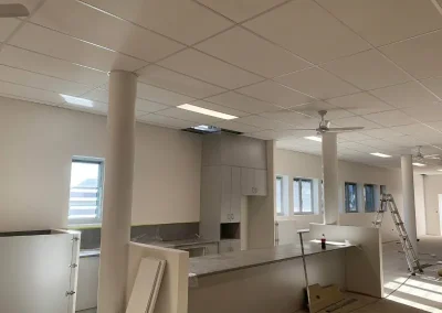 Completed suspended ceiling in Wynnum with grid panels fitted around light fixtures and ceiling fans