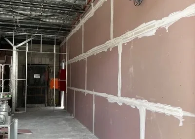 Plasterboard installer work in Toowong with wall sheets jointed along a commercial corridor frame