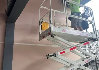 Plasterer in Milton on an elevated platform working on exterior eave cladding