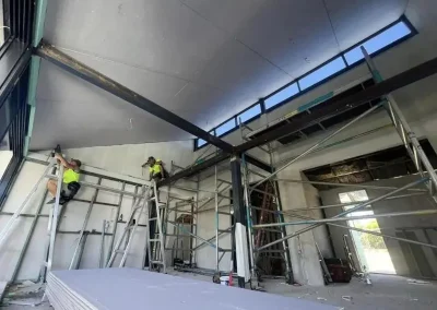Plastering contractors in Chapel Hill fitting ceiling sheets at a high raking commercial roofline